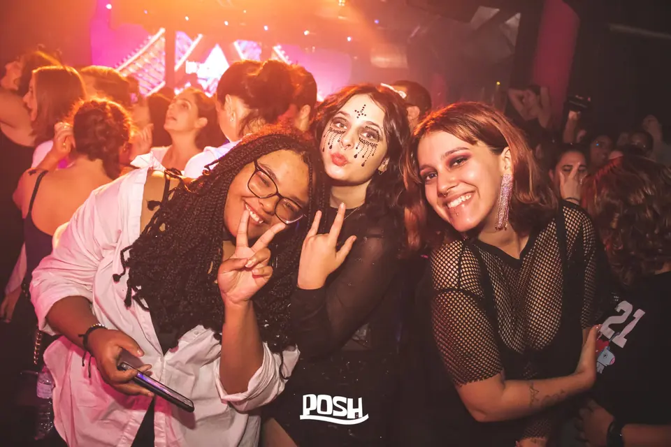 Três amigas a sorrir e a fazer o sinal de paz na pista
