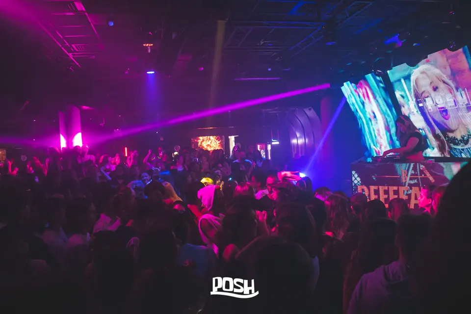Pista cheia com a DJ e os ecrãs de K-pop ao fundo